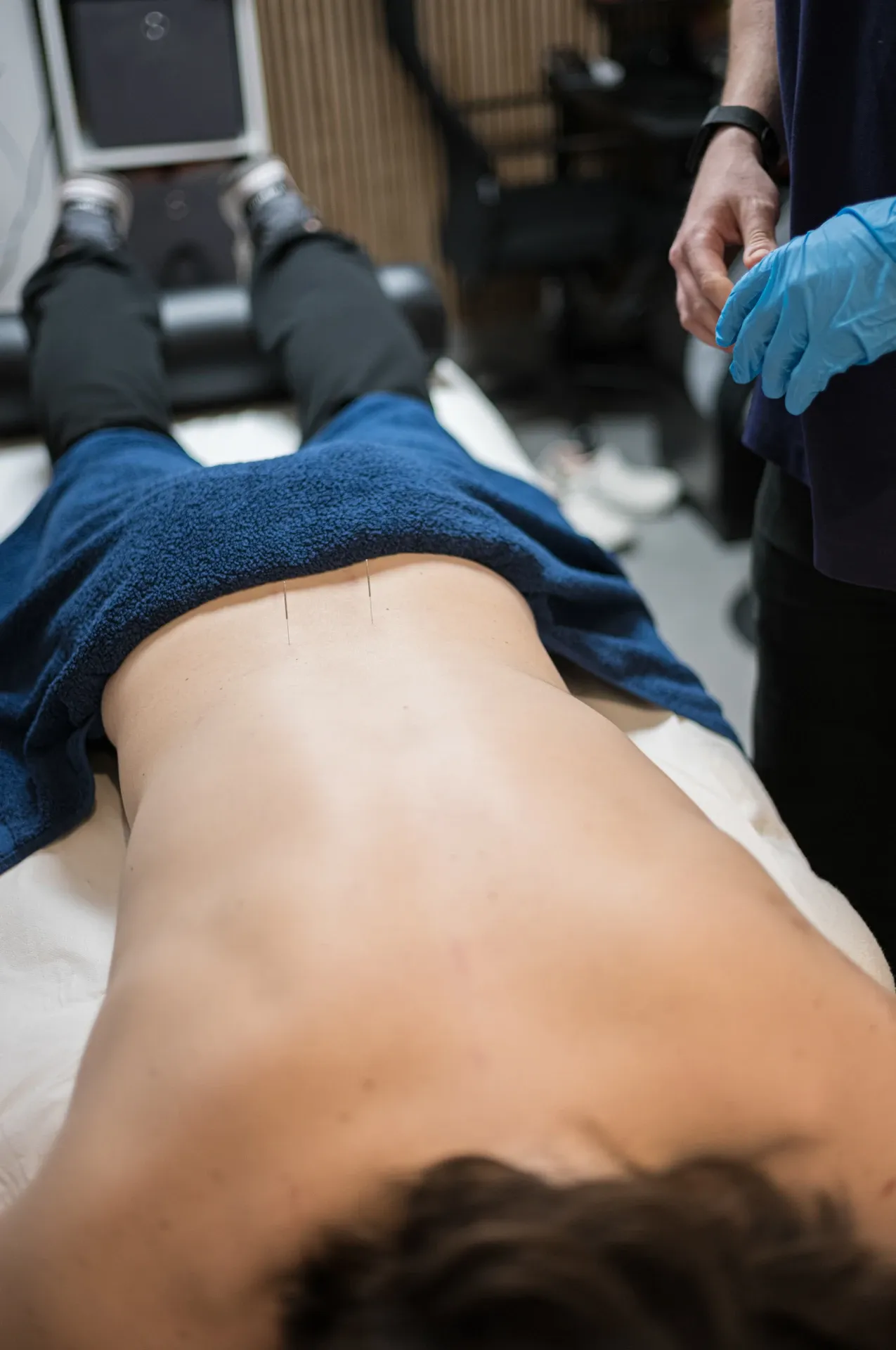 Masaje terapéutico con el paciente boca abajo sobre toalla azul, en la clínica de Iñigo Goikoetxea, fisioterapeuta en Bilbao