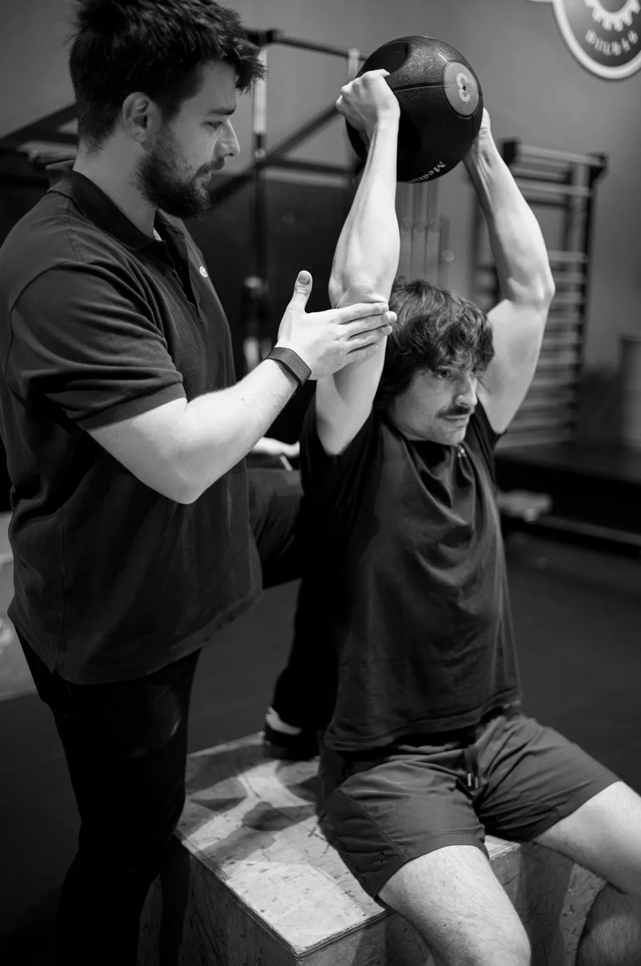 Entrenamiento guiado con press de kettlebell sobre la cabeza, blanco y negro, en la clínica de Iñigo Goikoetxea, fisioterapeuta en Bilbao
