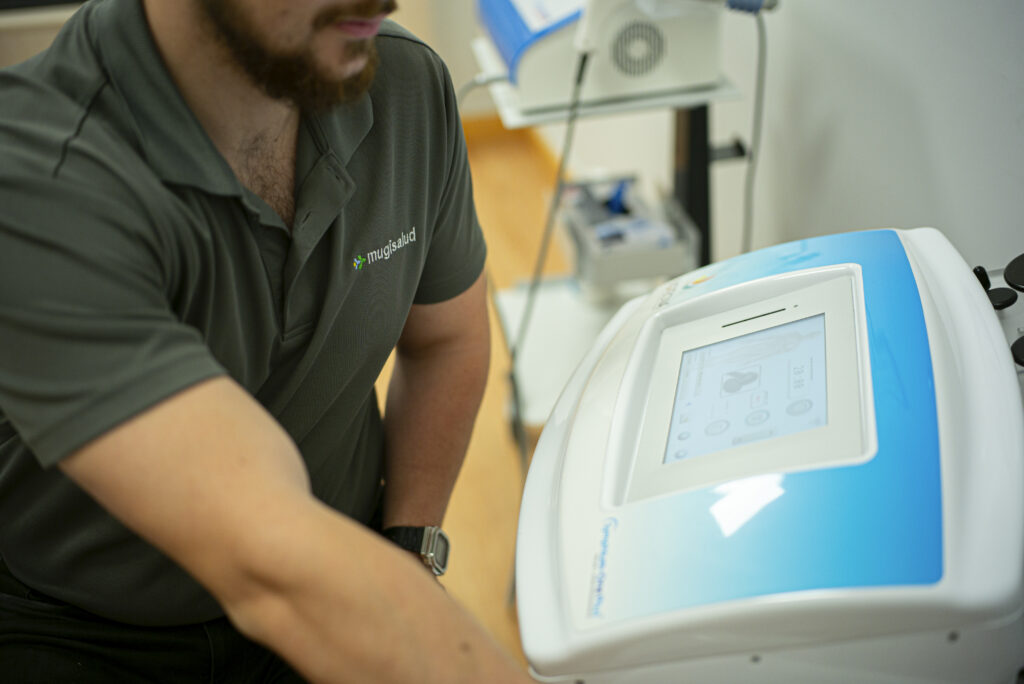 Fisioterapeuta ajustando los parámetros de un equipo de electroterapia en la clínica
